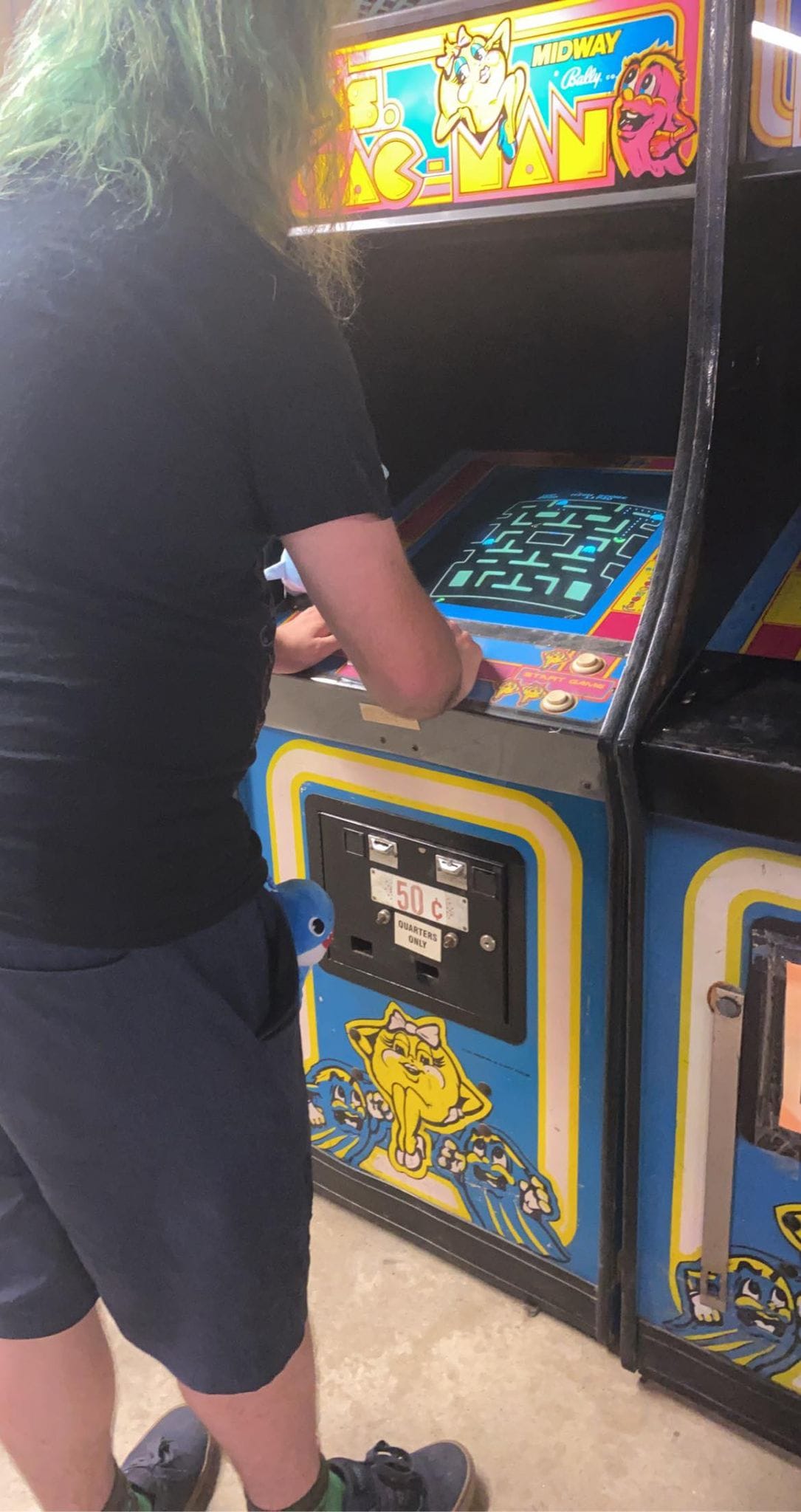 A man with green hair plays a Ms. Pacman arcade game, Photo 2